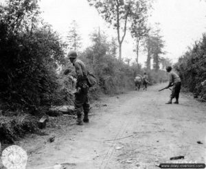 Des soldats s’appuient mutuellement au passage des trouées dans les haies dans le secteur de Saint-Lô. Photo : US National Archives