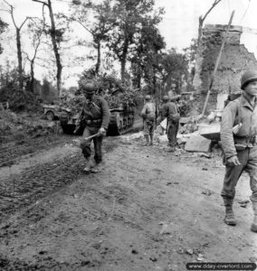 Un char Sherman progresse aux côtés de l’infanterie tandis qu’un transmetteur répare les lignes téléphoniques à Saint-Lô. Photo : US National Archives