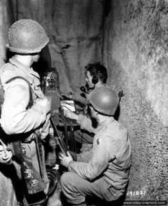 Installation d’un central téléphonique pour un poste de commandement dans une cave du centre-ville de Saint-Lô. Photo : US National Archives