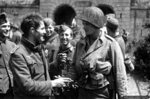 28 juin 1944 : le soldat américain James Fergusen serre la main avec des prisonniers allemands qui semblent heureux de leur sort à Cherbourg. Photo : US National Archives