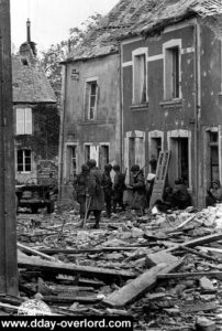 16 juin 1944 à Saint-Sauveur-le-Vicomte : le colonel Vandervoort du 505th PIR et ses béquilles, s'étant cassé la cheville lors de son atterrissage (Robert Capa est accroupi à droite). Photo : US National Archives