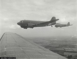 Au-dessus de l'Angleterre, des C-47 en vol de formation peu avant l'opération Neptune. Les appareils portent déjà les "D-Day stripes", bandes blanches utilisées pour la reconnaissance des unités antiaériennes. Photo : US National Archives