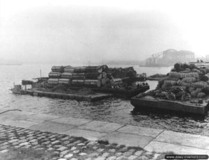 3 août 1944 : déchargement de matériels transportés sur des plates-formes flottantes, à proximité du quai du Homet à Cherbourg. Photo : US National Archives