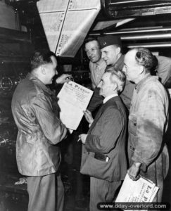 Deux capitaines américains observent la une du journal « La Presse Cherbourgeoise », édité à Cherbourg avec le concours des Américains. Photo : US National Archives