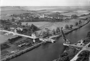Carte postale d'après-guerre de Bénouville, prise en direction du nord-nord-ouest et de son fameux pont à bascule devenu le "Pegasus Bridge". En haut à droite de la photo, les maisons d'Ouistreham-Riva-Bella sont visibles. Photo : DR