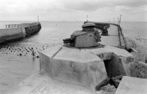 L'entrée du port de Grandcamp, bloquée par un filet métallique et défendue par un tobrouk surmonté d'une tourelle de char Renault FT en calibre 37 m, après la libération de 1944. Photo : US National Archives