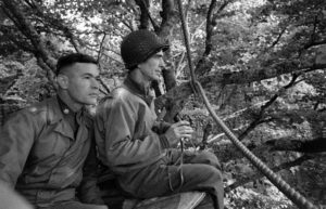 A Cerisy-la-Forêt, le Brigadier General George P. Hays (à droite), commandant la 2nd Division Artillery, observe la ligne de front à partir d'un poste d'observation de fortune installé au sommet d'un arbre. A ses côtés, le Lieutenant Colonel Richard C. Carpenter, commandant le 12th (M) Field Artillery Battalion. Photo : US National Archives