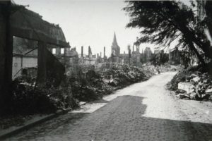 La rue d'Orbec (aujourd'hui rue du docteur Lesigne) à Lisieux au milieu des ruines après les bombardements de 1944. La cathédrale est visible en arrière-plan. Photo : DR