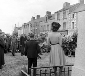 4 juillet 1944 : à l'occasion de la fête nationale américaine, la population et les militaires de la 2nd (US) Infantry Division se rassemblent devant le monument aux Morts de Cerisy-la-Forêt où une cérémonie a été organisée et les hymnes nationaux sont joués. Le maire, Eugène Godin, ainsi que le Major General Walter M. Robertson (au centre de la photo, casque contre le cœur), commandant la division américaine, sont présents. Photo : US National Archives