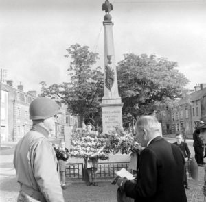 4 juillet 1944 : à l'occasion de la fête nationale américaine, le maire de Cerisy-la-Forêt, Eugène Godin, et le Major General Walter M. Robertson, commandant la 2nd (US) Infantry Divison, participent à la cérémonie organisée devant le monument aux Morts. Le maire prononce son discours. Photo : US National Archives