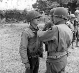 Cérémonie de remise de décorations commandée par le Major General Walter M. Robertson, 2nd (US) Infantry Division, durant laquelle un de ses subordonnés reçoit une mdéaille à Cerisy-la-Forêt. Photo : US National Archives