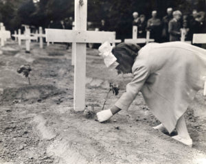 14 juillet 1944 : une fillette dépose des fleurs sur des tombes du cimetière militaire temporaire n°2 de Sainte-Mère-Eglise, le jour de l'enterrement du Brigadier General Theodore Roosevelt Jr. Photo : US National Archives