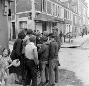 Le sergent Roland des Autels (casque et moustache) du CIC (Counter Intelligence Corps) s'entretient avec des habitants de la commune de Grandcamp-les-Bains, sur l'actuelle rue de la libération. Photo : US National Archives