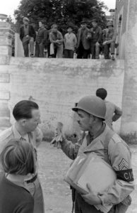 A Grandcamp, le sergent Roland des Autels du CIC (Counter Intelligence Corps) s'entretient avec des civils à Grandcamp-les-Bains. Photo : US National Archives