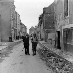 Le sergent Roland des Autels du CIC (Counter Intelligence Corps) et Pierre Ferrari, conseiller municipal de Grandcamp, circulent le long de l'actuelle rue Aristide Briand. Photo : US National Archives