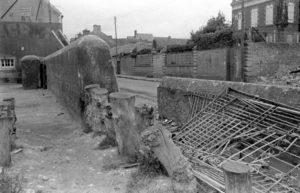 Le mur antichar interdisant l'accès au port de Grandcamp-les-Bains, à l'intersection de l'actuelle rue Aristide Briand et du quai Chéron. Photo : US National Archives