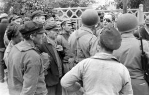 Juin 1944 : des soldats américains s'entretiennent avec des civils habitants Grandcamp peu après la libération. Photo : US National Archives