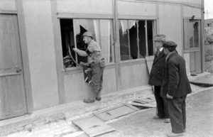 A Grandcamp, le sergent Roland des Autels du CIC (Counter Intelligence Corps) et Pierre Ferrari (à au milieu), conseiller municipal de Grandcamp, observent les vestiges d'un bâtiment du centre-ville. Photo : US National Archives