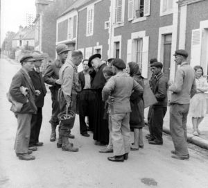 Le sergent Roland des Autels (casque à la main) du CIC (Counter Intelligence Corps) s'entretient avec des habitants de la commune de Grandcamp-les-Bains, sur l'actuelle rue de la libération. Photo : US National Archives