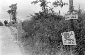 Rue du Petit Maisy à Grandcamp-les-Bains, des panneaux indiquent la présence de mines. Photo : US National Archives