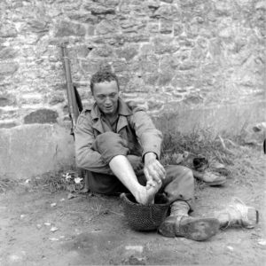 Un soldat américain appartenant à la 8th (US) Infantry Division profite d'une pause dans le secteur d'Avranches pour se laver les pieds, utilisant son casque à cet effet. Photo : US National Archives
