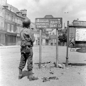 Un soldat américain observe un panneau Place Vauban à Carentan. Photo : US National Archives