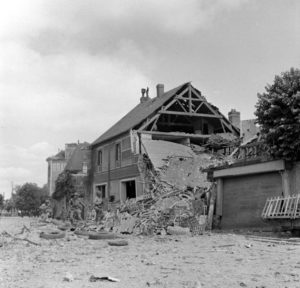 Des parachutistes américains de la 101st (US) Airborne Division patrouillent le long de la place du Marché aux Pommes à Carentan. Photo : US National Archives