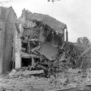 Une maison effondrée suite aux bombardements, rue du Docteur Caillard à Carentan. A noter : un drapeau anglais a été planté dans les décombres. Photo : US National Archives