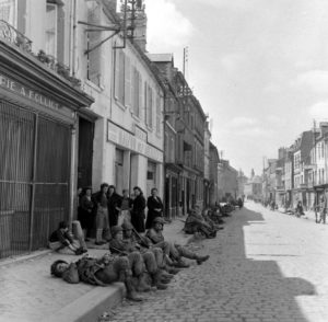 Épuisés par les éprouvants combats qu'ils viennent de livrer, des parachutistes américains de la 101st (US) Airborne Division profitent d'une sieste le long de la rue Holgate à Carentan. Photo : US National Archives