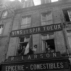 Des habitants de Carentan, Place de la République, parent le bâtiment d'un drapeau français pour célébrer la libération. Photo : US National Archives