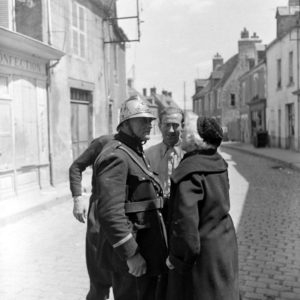 Un pompier français, qui a revêtu son plus bel uniforme à l'occasion de la libération, échange avec des habitants de Carentan. Photo : US National Archives