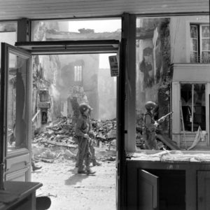 Des parachutistes américains appartenant à la HHQ Company, 501st Parachute Infantry Regiment, 101st (US) Airborne Division, patrouillent le long de la rue Holgate à Carentan. Photo : US National Archives