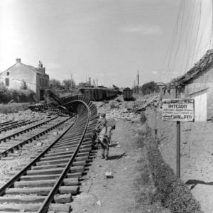 Des soldats américains patrouillent le long des voies ferrées soufflées par les bombardements à Carentan. Photo : US National Archives