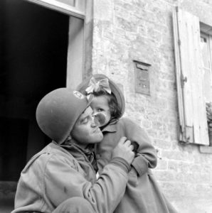 Un correspondant de guerre américain pose avec une fillette à Carentan. Photo : US National Archives