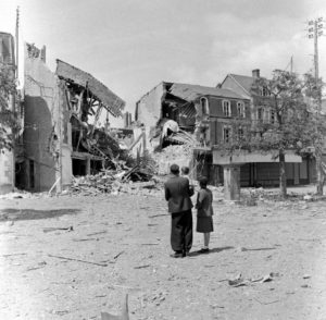 Des civils observent une maison effondrée suite aux bombardements, rue du Docteur Caillard à Carentan. Photo : US National Archives