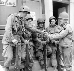 Distribution de cigarettes entre ces parachutistes américains appartenant au 2nd Battalion du 501st Parachute Infantry Regiment, 101st (US) Aiborne Division à Carentan. Photo : US National Archives