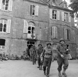 Des cadres de l'équipe médicale et des pensionnaires américains devant l'infirmerie tenue par le 308th Medical Battalion, 83rd (US) Infantry Division au numéro 45 rue Holgate à Carentan, dans l'hôtel Durand de la Borderie-Énouf. Photo : US National Archives