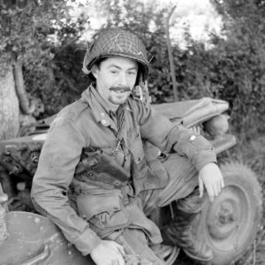 Juin 1944 : un parachutiste américain assis au bord d'une Jeep au campement provisoire de l’état-major de la 101st (US) Airborne Division, situé au bassin à flot à Carentan. Photo : US National Archives