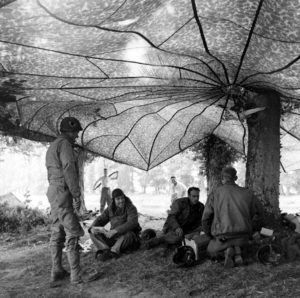 Juin 1944 : des parachutistes américains à l'abri sous des parachutes, au campement provisoire de l’état-major de la 101st (US) Airborne Division, situé au bassin à flot à Carentan. Deux d'entre eux font leur toilette au soleil en arrière-plan. Photo : US National Archives