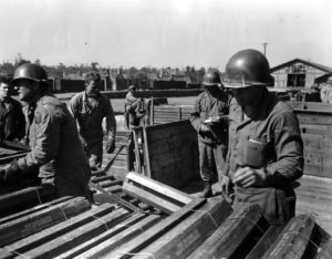 15 août 1944 : en gare de Carentan, des sapeurs américains appartenant à la 1st Engineer Special Brigade transportent des caisses d'obus de 76 mm destinés aux chars Sherman équipés du canon M1 et M1A1. Photo : US National Archives