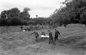 12 juillet 1944 : mise en bière de corps de soldats allemands au cimetière militaire d'Orglandes, par les prisonniers allemands sous contrôle de la police militaire américaine. Photo : US National Archives
