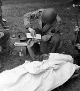 12 juillet 1944 : préparation à la mise en bière de soldats allemands et récupération des empreintes des défunts par des Américains appartenant à la 4th Platoon, 603rd Quartermaster Graves Registration Company (First US Army) au cimetière militaire d'Orglandes. Photo : US National Archives