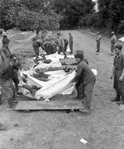 12 juillet 1944 : mise en bière de corps de soldats allemands au cimetière militaire d'Orglandes, par les prisonniers allemands sous contrôle de la police militaire américaine. Photo : US National Archives