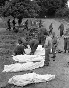 12 juillet 1944 : mise en bière de corps de soldats allemands au cimetière militaire d'Orglandes, par les prisonniers allemands sous contrôle de la police militaire américaine. Photo : US National Archives