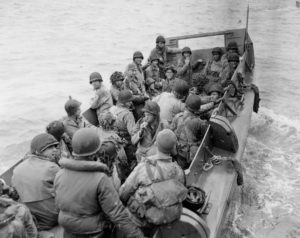 8 juin 1944 : au large d'Utah Beach dans la Manche, des pilotes de planeur sont transportés dans un chaland LCVP en direction d'un navire de transport avant de rejoindre l'Angleterre. Beaucoup d'entre eux ont encore le visage noirci par le camouflage. Photo : US National Archives