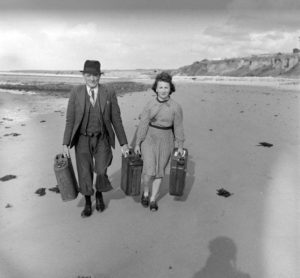 Juin 1944 : des civils transportent des jerrycans sur la plage du Pont du Hable, à proximité de Grandcamp-les-Bains. Les Alliés incitaient à ce que ces nourrices leur soient rapportées et récompensaient les civils qui en apportaient. Photo : US National Archives