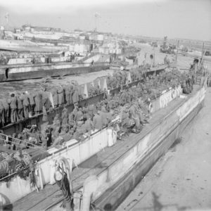 7 juin 1944 : des prisonniers allemands attendent le départ vers l'Angleterre à bord du LCT 7074 sur le secteur Jig Green de Gold Beach. En arrière-plan, le LCT 886, endommagé par les combats du Jour-J. Photo : IWM B 5135