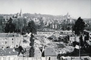 Ruines de Lisieux en 1944 après les bombardements alliés. Photo prise depuis le coteau de la vallée de la Touques. La basilique Saint-Thérèse (à droite) et la cathédrale Saint-Pierre sont visibles dans les décombres. Photo : DR