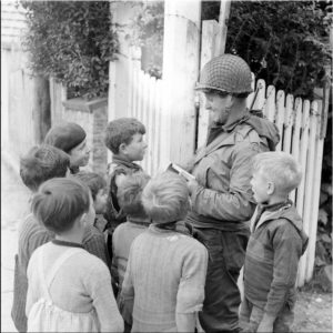Un soldat américain attire la curiosité d'enfants à Grandcamp-les-Bains. Photo : US National Archives
