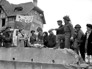Devant la "Maison des Canadiens, des soldats du régiment francophone de La Chaudière et des civils normands savourent la libération. Photo : Archives Canada